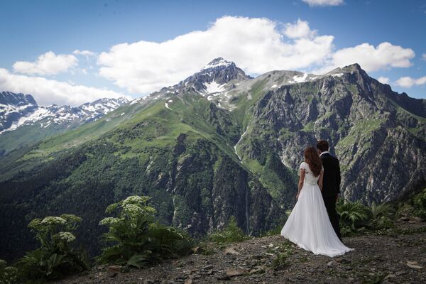 متزوجان حديثا على خلفية منتجع دومباي الجبلي في قراتشاي - تشيركيسيا شمال القوقاز، روسيا الاتحادية - سبوتنيك عربي