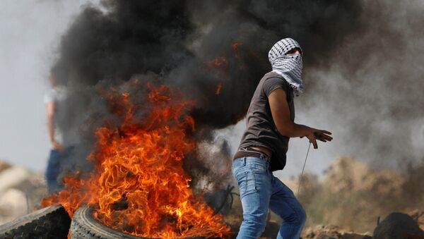  فلسطينيون ملثمون بجانب الإطارات المحترقة خلال اشتباكات مع القوات الإسرائيلية فى قرية الخبر بالضفة الغربية بالقرب من رام الله - سبوتنيك عربي