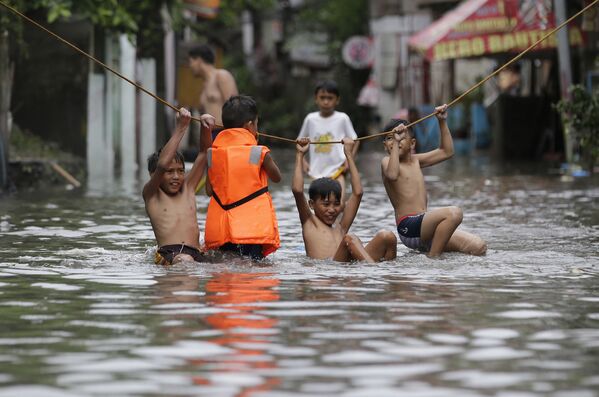 فتيان يلعبون خارج منازلهم المغمورة إثر الأمطار الغزيرة التي سببتها العاصفة الاستوائية نيسات أجزاء من مانيلا الكبرى، الفلبين 27 يوليو/ تموز 2017 - سبوتنيك عربي