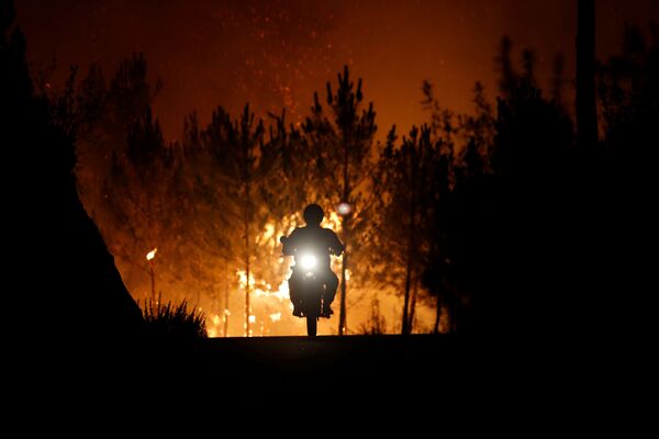 رجل اطفاء راكبا دراجته النارية، يهرب بعيدا عن حريق الغابات المندلعة بالقرب من قرية ماكاو، بالقرب من كاستيلو برانكو، البرتغال 26 يوليو/ تموز 2017 - سبوتنيك عربي