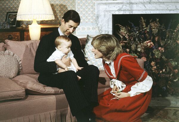 الأمير ويليام (6 شهور) بين والديه الأمير تشارلز ووالدته الأميرة ديانا  في لندن، 22 ديسمبر/ كانون الأول عام 1982 - سبوتنيك عربي