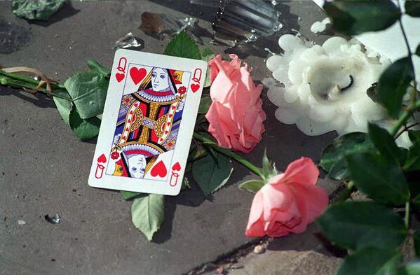 ورقة لعبة الشدّة الملكة ضمن أكاليل الأزهار التي وضعت أمام قصر بكنغهام الملكي في لندن في ذكرى رحيل الأميرة ديانا، عام 1997 - سبوتنيك عربي