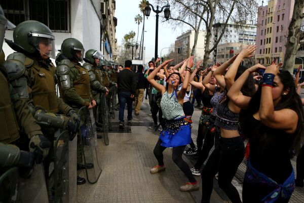 متظاهرون يرقصون أمام شرطة الشغب في سانتياغو، تشيلي 5 سبتمبر/ أيلول 2017 - سبوتنيك عربي