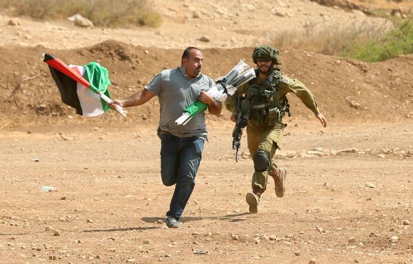 جندي إسرائيلي يركض خلف متظاهر فلسطيني خلال اشتباكات دارت بين المتظاهرين والجيش الإسرائيلي في بلدة طوباس بالضفة الغربية، فلسطين 27 سبتمبر/ أيلول 2017 - سبوتنيك عربي