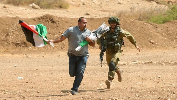 جندي إسرائيلي يركض خلف متظاهر فلسطيني خلال الاشتباكات دارت بين المتظاهرين والجيش الإسرائيلي في بلدة طوباس بالضفة الغربية، فلسطين 27 سبتمبر/ أيلول 2017 - سبوتنيك عربي