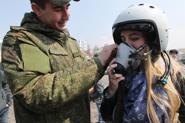 عسكري يساعد فتاة على ارتداء خوذة طيار خلال المعرض العسكري في فلاديفوستوك - سبوتنيك عربي