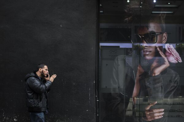 رجل يتحدث على الهاتف المحمول على خلفية صورة إعلانية في نيويورك، الولايات المتحدة 14 نوفمبر/ تشرين الثاني 2017 - سبوتنيك عربي