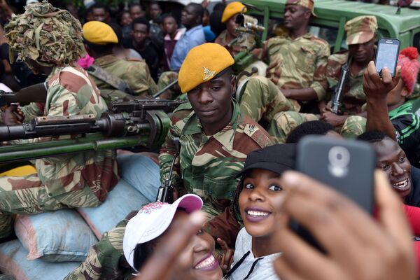 فتيات يلتقطن صورة سيلفي على خلفية جنود من الجيش الوطني في هراري، زيمبابوي 18 نوفمبر/ تشرين الثاني 2017 - سبوتنيك عربي
