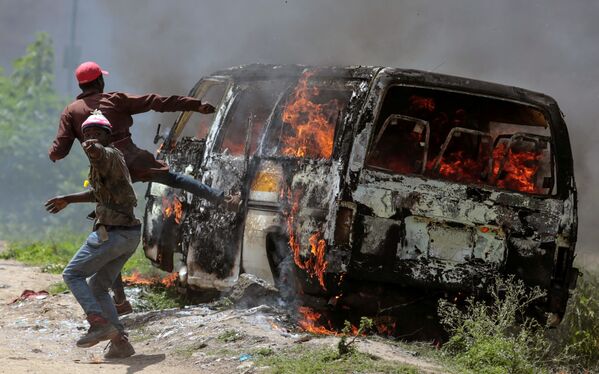 مؤيدون لحركة المعارضة الكينية التحالف الفائق الوطني بالقرب من السيارة المحترقة في إمباكاسي، كينيا - سبوتنيك عربي