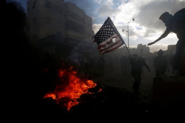 متظاهرون فلسطينيون يحرقون العلم الأمريكي احتجاجا على قرار الرئيس دونالد ترامب بشأن القدس، بالقرب من مستوطنة إسرائيلية في بيت إيل، الضفة الغربية، 7 ديسمبر/ كانون الأول 2017 - سبوتنيك عربي