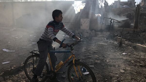 طفل بجانب مبنى مدمر في قطاع غزة - سبوتنيك عربي