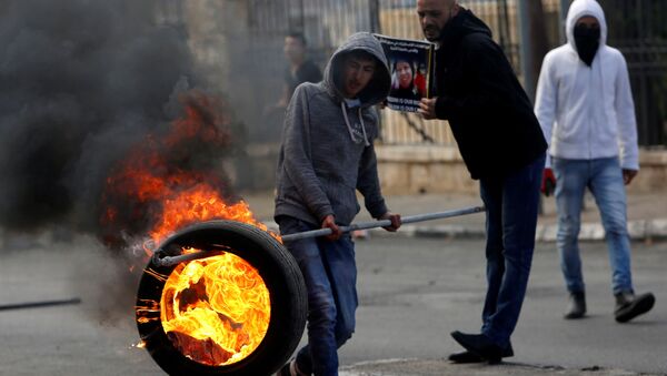 فلسطيني يحمل إطارا مشتعلا خلال المواجهات مع الشرطة الإسرائيلية في بيت لحم، الضفة الغربية، فلسطين 27 ديسمبر/ كانون الأول 2017 - سبوتنيك عربي