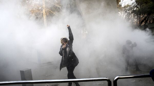 طالبة جامعية في مظاهرة داخل جامعة طهران وقت إلقاء قنبلة دخان من قبل الشرطة الإيرانية لمكافحة الشغب - سبوتنيك عربي