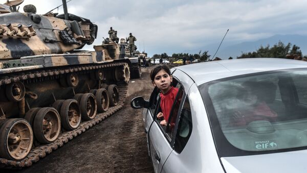 طفلة تركية تنظر عبر نافذة سيارة على خلفية تجمع لدبابات الجيش التركي على الحدود السورية التركية في هاتاي، 21 يناير/ كانون الثاني 2018 - سبوتنيك عربي