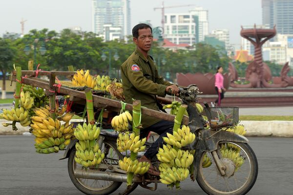 رجل كمبودي يركب دراجة نارية محملة بالموز في شارع بمدينة بنوم بنه، كومبوديا 23 يناير/ كانون الثاني 2018 - سبوتنيك عربي