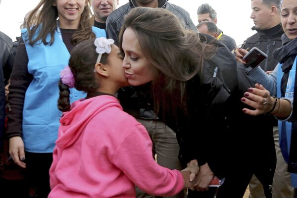 سفيرة الأمم المتحدة للنوايا الحسنة، أنجولينا جولي تقبل طفلة لاجئة سورية، خلال زيارتها لمخيم الزعتري للاجئين السوريين في المفرق شمال الأردن - سبوتنيك عربي