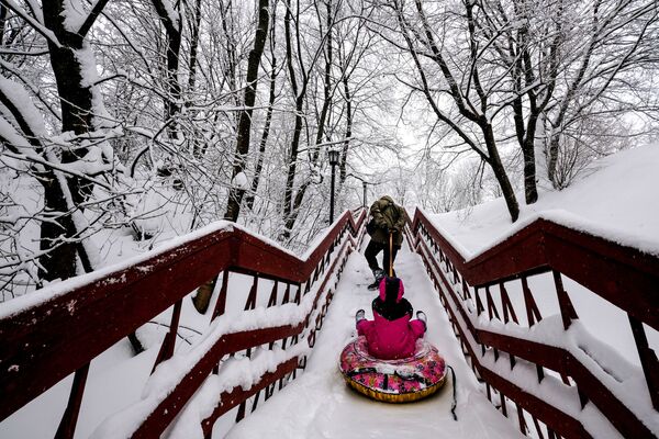 أب يجر زلاجة مع ابنته على درج في حديقة كولومينسكوي في موسكو - سبوتنيك عربي