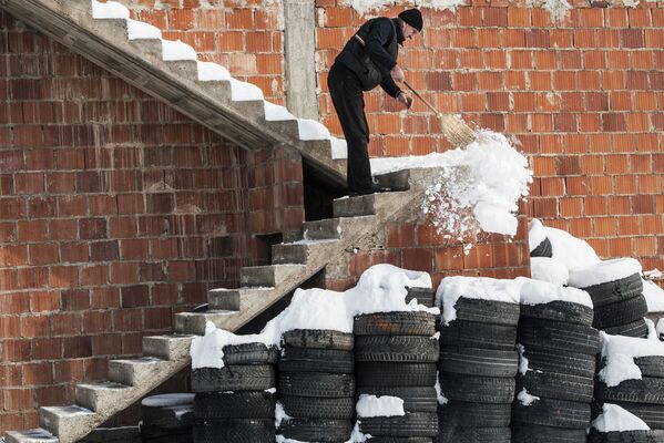 رجل يقوم بتنظيف الثلج على درج المنزل في قرية مرامور، بريشتينا، سيبيريا 27 فبراير/ شباط 2018 - سبوتنيك عربي