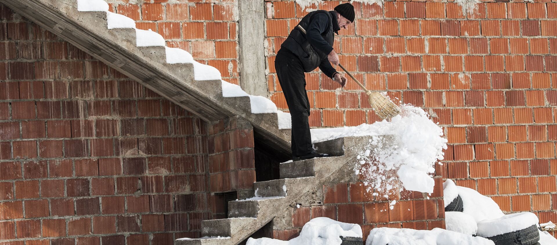 رجل يقوم بتنظيف الثلج على درج المنزل في قرية مرامور، بريشتينا، سيبيريا 27 فبراير/ شباط 2018 - سبوتنيك عربي, 1920, 08.05.2021
