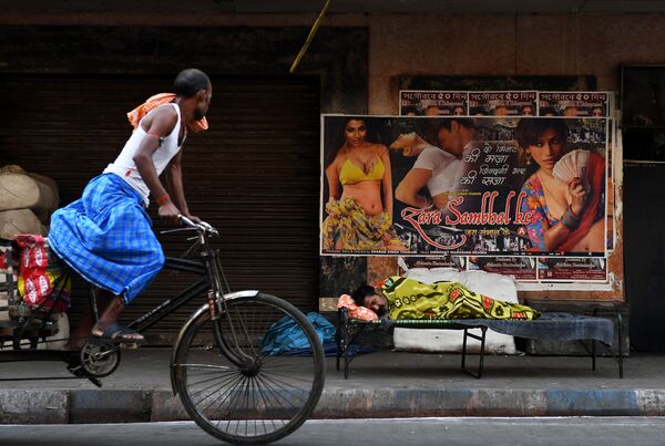 رجل يركب دراجة هوائية على خلفية لوحة إعلانات للسينما في كلكتا، الهند 12 مارس/ آذار 2018 - سبوتنيك عربي