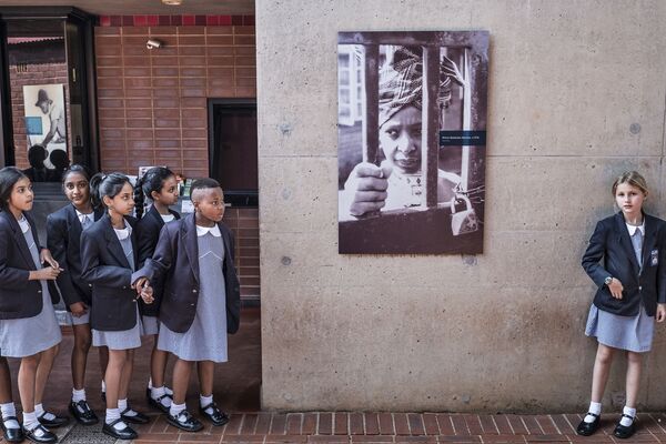 أطفال المدارس في جنوب أفريقيا يقفون أمام صورة للناشطة المناهضة لنظام الفصل العنصري في جنوب أفريقيا ويني ماديكيزيلا - مانديلا، الزوجة السابقة لزعيم المؤتمر الوطني الأفريقي نيلسون مانديلا، على جدار منزلها في سويتو 3 أبريل/ نيسان  2018 - سبوتنيك عربي
