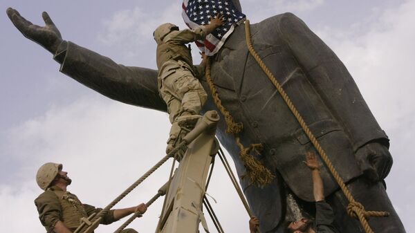 مجند أمريكي يضع علم الولايات المتحدة على رأس تمثال صدام حسين في عام 2003 في بغداد - سبوتنيك عربي