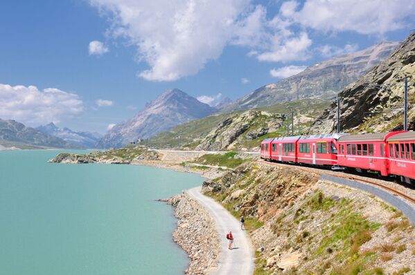 قطار يمر عبر بحيرة لاغو بيانكو في ممر بيرنينا في جبال الألب الإيطالية - سبوتنيك عربي