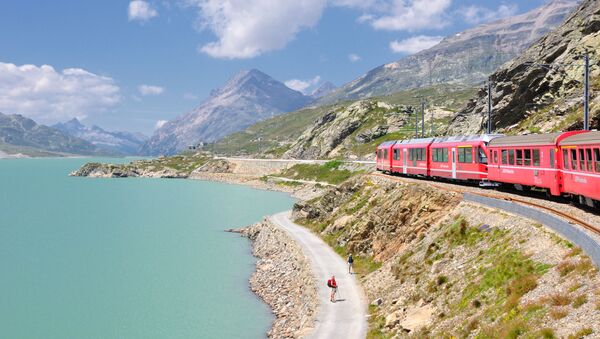  قطار يمر عبر بحيرة لاغو بيانكو في ممر بيرنينا في جبال الألب الإيطالية - سبوتنيك عربي