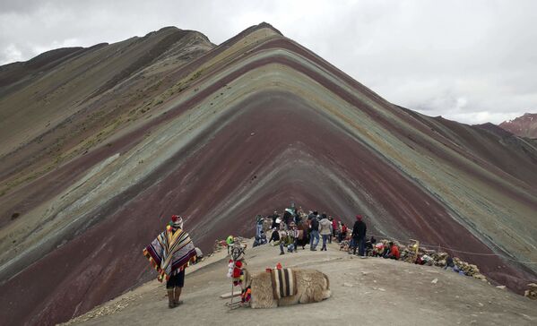 رجل الأنديز مع اللاما بينما يستقبل السياح في إحدى مناطق العجائب الطبيعية في جبل راينبو في بيتوماركا، بيرو. - سبوتنيك عربي