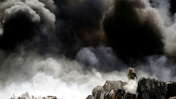 رجل إطفاء يخمد حريق في كومة من الإطارات القديمة في مركز إعادة التدوير في سيوداد خواريز، المكسيك 2 مايو/ أيار  2018 - سبوتنيك عربي
