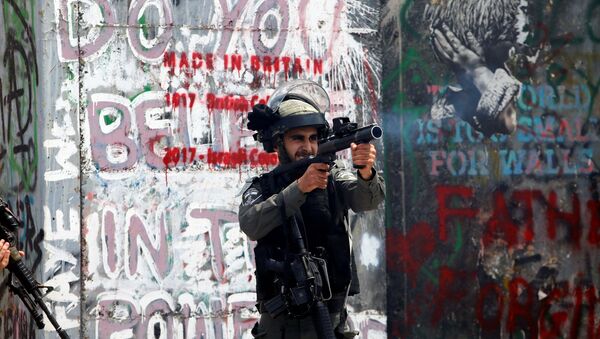 شرطي الحدود الإسرائيلي يطلق الغاز المسيل للدموع على المتظاهرين الفلسطينيين في بيت لحم خلال احتجاجات ضد نقل السفارة الأمريكية إلى القدس عشية الذكرى الـ 70 لـ النكبة، الضفة الغربية، فلسطين 14 مايو/ أيار 2018 - سبوتنيك عربي