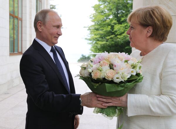 الرئيس فلاديمير بوتين يهدي باقة من الأزهار لمستشارة ألمانيا أنغيلا ميركل لدى وصولها إلى مدينة سوتشي، روسيا 20 مايو/ أيار 2018 - سبوتنيك عربي