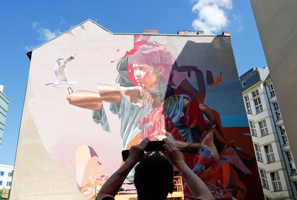 جدارية للفنانان تلموميل وجيمس بولوف (TelmoMiel and James Bullough) كجزء من مهرجان برلين للجداريات 2018 الأول من نوعه، حيث يقوم الفنانون المدنيون المحليون والدوليون بإنشاء معرض كبير في الهواء الطلق لإثراء المساحات الحضرية في برلين، ألمانيا  21 مايو/ أيار 2018 - سبوتنيك عربي