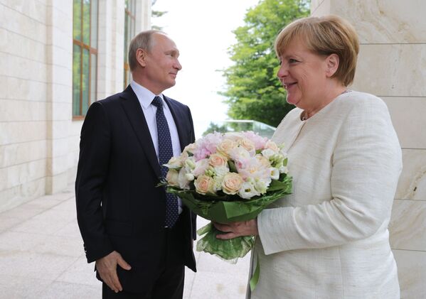 الرئيس فلاديمير بوتين يهدي باقة من الأزهار لمستشارة ألمانيا أنغيلا ميركل لدى وصولها مدينة سوتشي، روسيا 20 مايو/ أيار 2018 - سبوتنيك عربي
