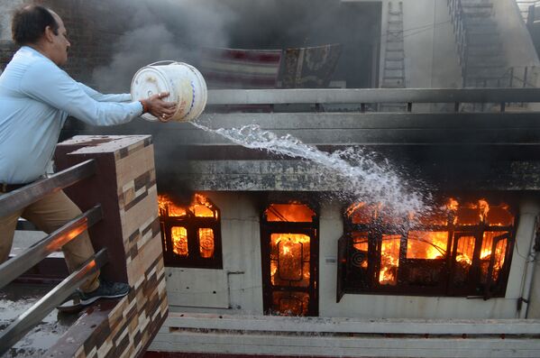 أحد السكان يحاول إخماد حريق في متجر كهربائي في أمريتسار، الهند في 20 مايو/ أيار 2018 - سبوتنيك عربي