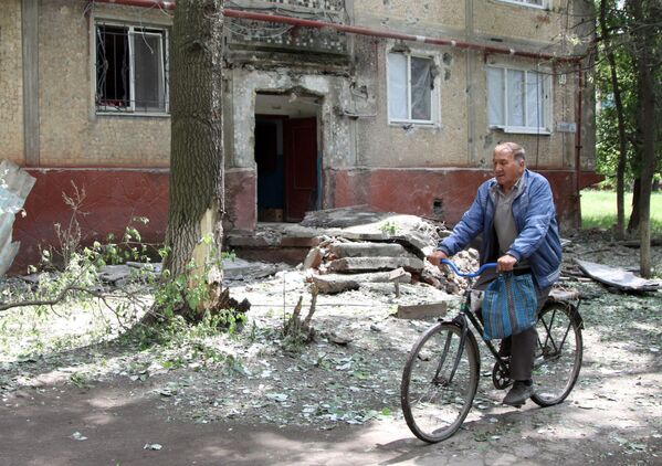 رجل يركب دراجة هوائية بجوار منزله في بلدة غورلوفكا في دونيتسك - سبوتنيك عربي