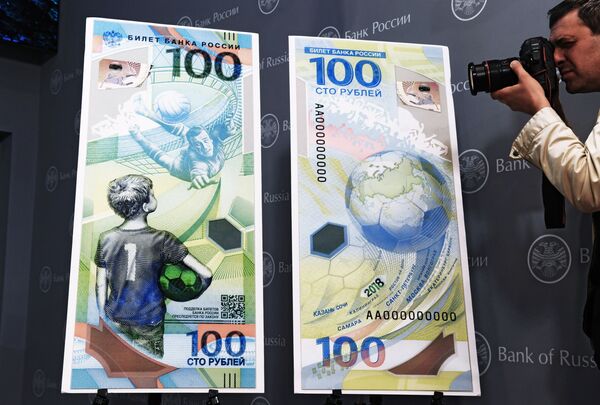 مصور صحفي يلتقط صورة لمجسم ورقة نقدية بلاستيكية من قيمة مائة روبل في ذكرى استضافة روسيا لمونديال كأس العالم لكرة القدم للمرة الأولى في تاريخها - سبوتنيك عربي