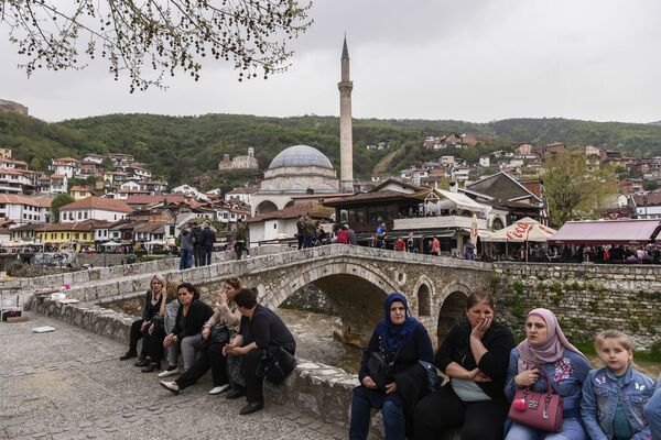 الناس يجلسون بجانب جسر حجري يطل على مدينة بريزرين، كوسوفو - سبوتنيك عربي