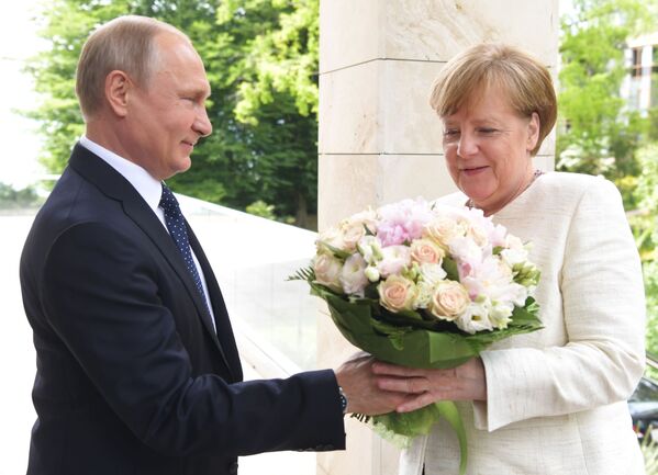 الرئيس فلاديمير بوتين يهدي باقة من الأزهار لمستشارة ألمانيا أنجيلا ميركل لدى وصولها مدينة سوتشي، روسيا  20مايو/ أيار 2018 - سبوتنيك عربي