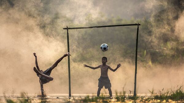 صبيان آسيون يلعبون كرة القدم في الريف - سبوتنيك عربي