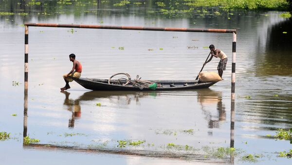القرويون الهنود المتضررون من الفيضانات يمرون في مراكبهم بجوار مرمى مغممور جزئيا في قرية موكاتا، على بعد 70 كم من جواهاتي، الهند 11 يوليو/ تموز 2013 - سبوتنيك عربي