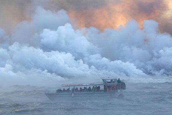 الناس يشاهدون من قارب سياحي بينما تتدفق الحمم البركانية في المحيط الهادئ في منطقة كابوهو، أثناء ثوران بركان كيلاويا في هاواي، الولايات المتحدة 4 يونيو/ حزيران 2018 - سبوتنيك عربي