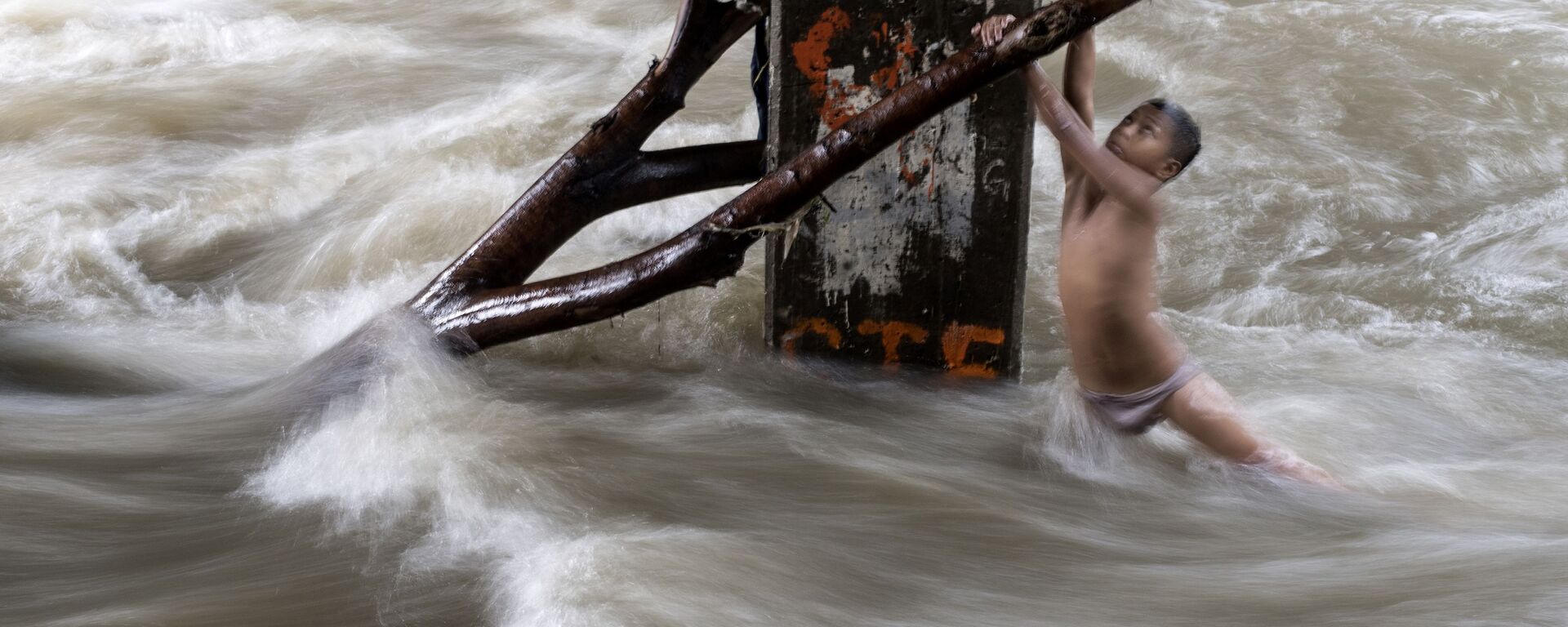 صبي يمسك بغصن شجرة خشية الانجرار في نهر فاض بسبب الأمطار الغزيرة في مانيلا، الفلبين 11 يونيو/ حزيران 2018 - سبوتنيك عربي, 1920, 29.10.2022