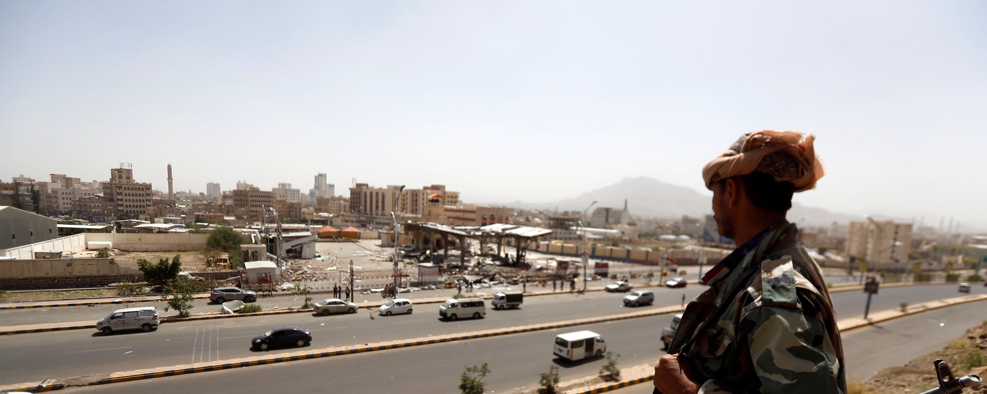 جندي يمني يقف أمام محطة وقود تعرضت للقصف في العاصمة صنعاء في اليمن - سبوتنيك عربي, 1920, 31.10.2021