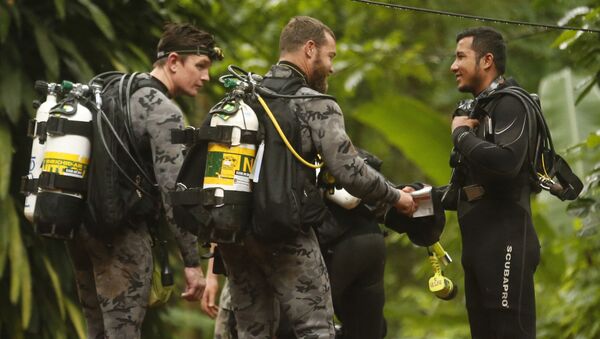 موظفو الشرطة الفيدرالية الأسترالية يتحدثون مع أحد عمال الإنقاذ التايلنديين قبل بدء عملية الإنقاذ - سبوتنيك عربي