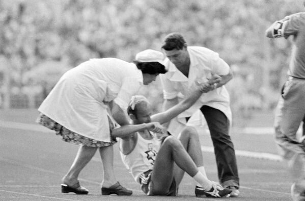 الأطباء الرياضيون يساعدون رياضيا مصابا على النهوض خلال  المسابقات في دورة الألعاب الصيفية الـ 22 في موسكو، 1980 - سبوتنيك عربي