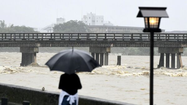 أحد السكان المحليين يشاهد جسر توجتسوا وتدفق نهر كاتسورا أسفله بسبب المطر الغزير في كيوتو في اليابان، 6 يوليو/تموز 2018 - سبوتنيك عربي