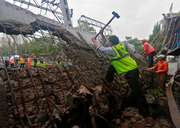 عمال الإنقاذ والسكك الحديدية يعملون في موقع الجسر الذي انهار فوق خطوط السكك الحديدية بعد هطول أمطار غزيرة في مومباي بالهند في 3 يوليو/ تموز 2018 - سبوتنيك عربي
