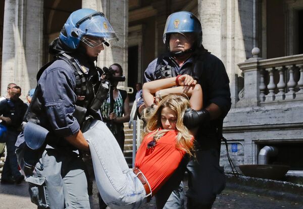 أفراد الشرطة الإيطالية يمسكون بأحد المتظاهرين خارج مبنى وزارة النقل، خلال احتجاجات ضد سياسة الحكومة حول الهجرة في روما، إيطاليا 11 يوليو/ تموز 2018 - سبوتنيك عربي