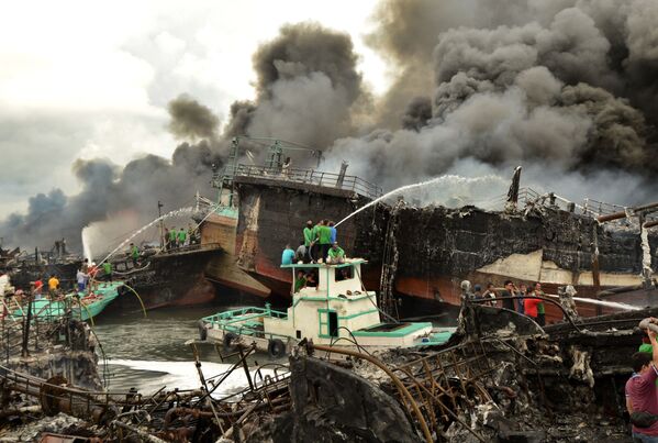 عمال إندونيسيون ورجال الإطفاء يخمدون حريق على قوارب الصيد في ميناء بينوا في دنباسار، في جزيرة بالي، إندونيسيا 9 يوليو/ تموز 2018 - سبوتنيك عربي